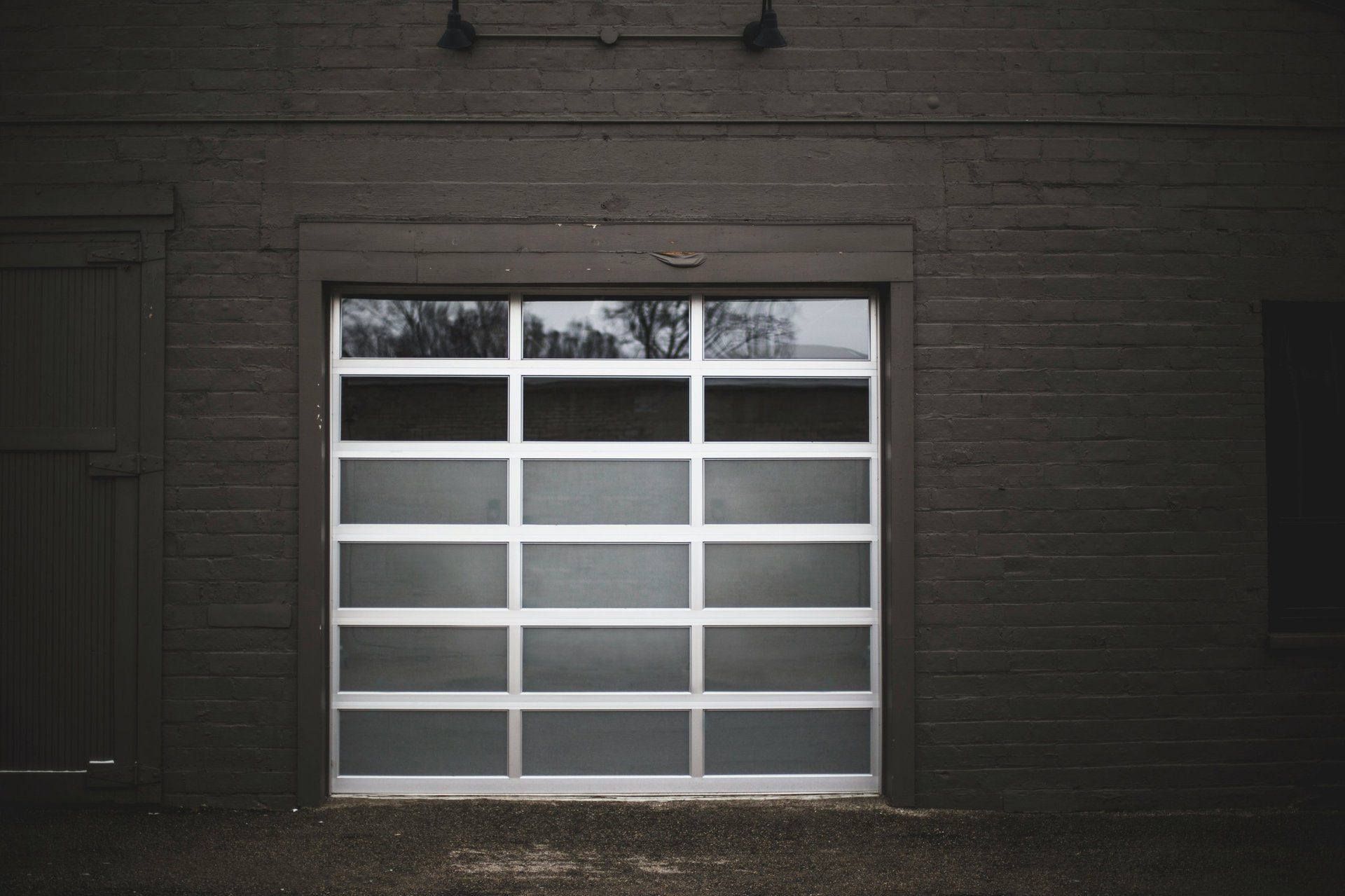 Modern white garage door with horizontal panels mounted on dark brick building facade